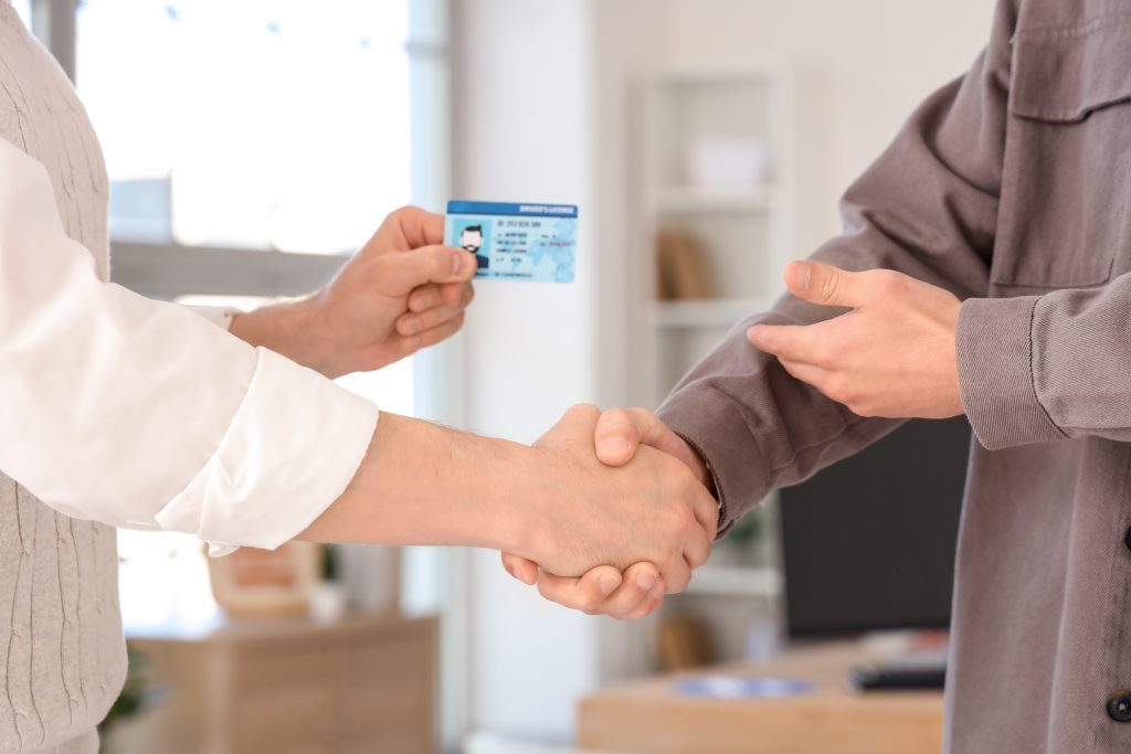 Male,Instructor,With,License,And,Man,Shaking,Hands,At,Driving